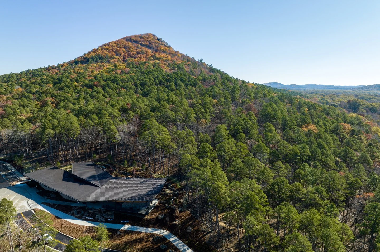 Wooded Arkansas hills beneath a clear blue sky